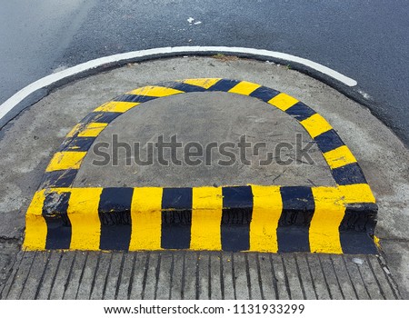 The yellow-black painting symbol at the u-turn junction median strip that warning car drivers to beware walking people.