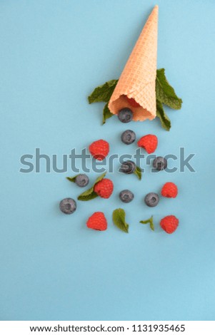 An ice cream cone with blueberries, raspberries and mint on a colorful background as a symbol of a refreshing summer fruity ice cream