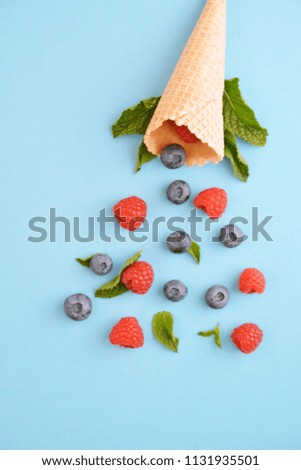 An ice cream cone with blueberries, raspberries and mint on a colorful background as a symbol of a refreshing summer fruity ice cream