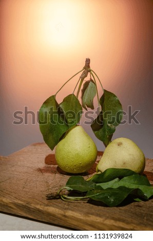 Two pears on a wooden board on a colored background.
