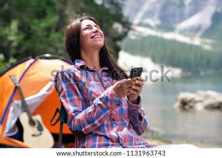 in mountains on vacation A girl uses a mobile phone or smartphone for texting,calling, take pictures, make selfies and video calls friends and family from home. Concept:holiday,technology,love,message
