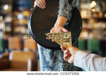 The hand of the waitress takes the tip. The waiter girl receives a tip from the client at the hotel bar. A bartender woman is happy to receive a tip at work. The concept of service. Royalty-Free Stock Photo #1131971006