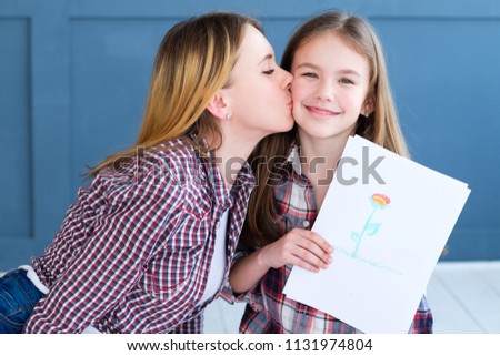 kid creativity and art. girl showing a drawing of flower. child leisure hobby and self expression. loving mom kissing her daughter
