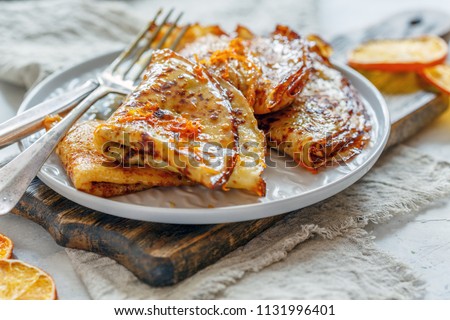 Crepe suzette with orange sauce for a delicious breakfast, selective focus. Royalty-Free Stock Photo #1131996401