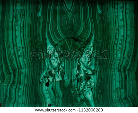 Green monolithic texture of the old stone (malachite) with cracks, scratches, lines, gap, rupture. Abstract symmetrical pattern. Photo from the historical museum
