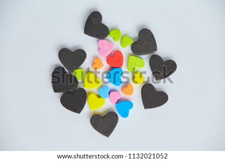 Colorful small hearts shaped in the middle of black hearts shapes. Minimal love concept. Flat lay.