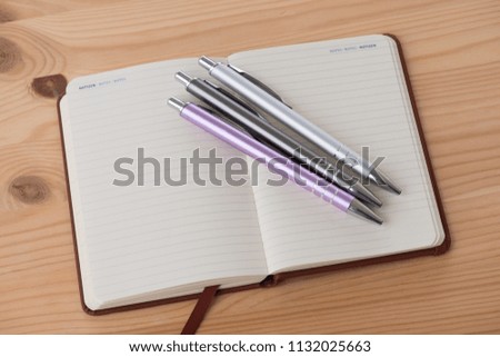 Empty booklet on a wooden table with a pen