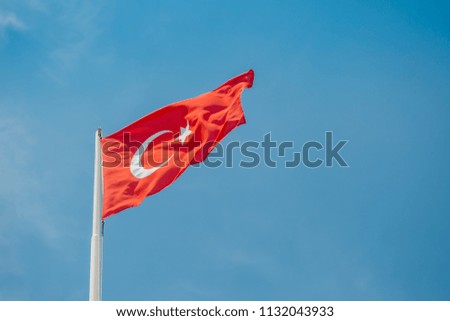 Large flag of Turkey is waving in the wind against the blue sky on the coast of the Mediterranean Sea