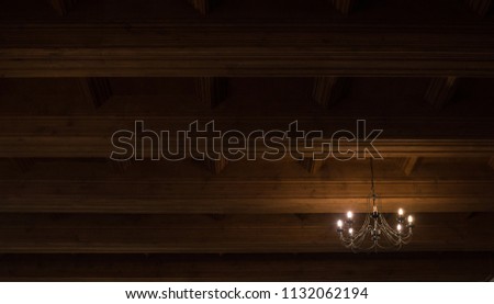 Historical decorative chandelier
on wooden ceiling creating mystic emotional background texture