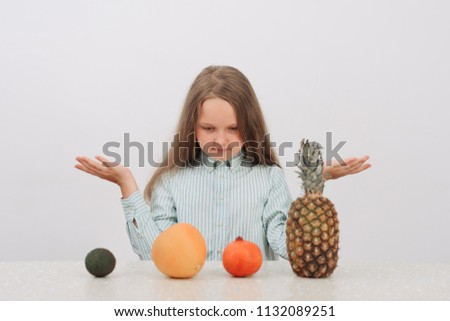 Cheerful little girl with fruits poses in studio.Healthy food.