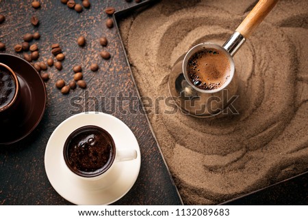 Traditional turkish coffee in cezve prepared on hot sand. Selective focus Royalty-Free Stock Photo #1132089683