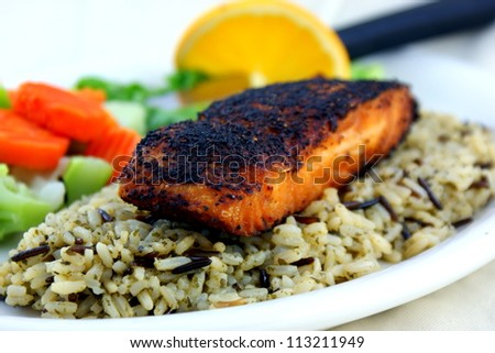 Blackened salmon served on wild rice with vegetables. Royalty-Free Stock Photo #113211949