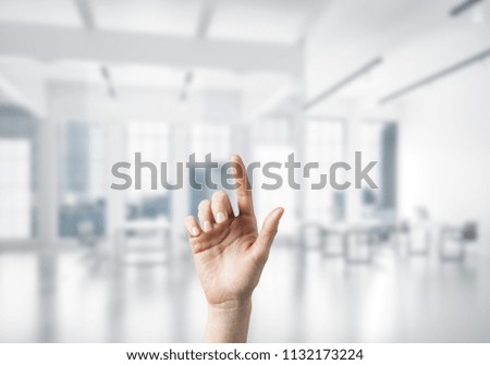 Close of woman hand touching screen with finger and office at background