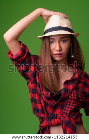 Young slim Asian woman against green background