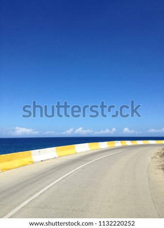 Two way road with concrete fence at the edge of the ocean. Barrier, guard rail, designed to prevent the exit of the vehicle from the curb, moving across the dividing strip.