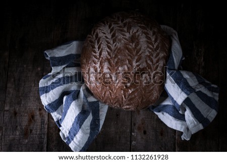 Beautiful Rye bread in a strong bakers hands, on a dark background, rustic photography
