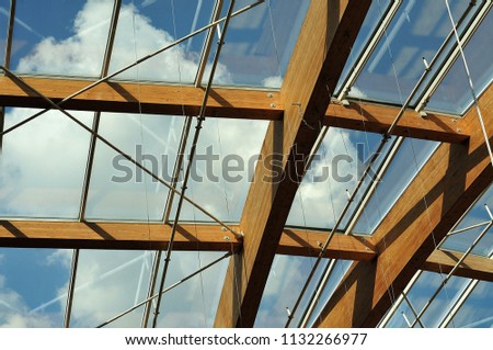 cloudy blue sky seen through transparent roof constructed with beams of glued laminated timber Royalty-Free Stock Photo #1132266977