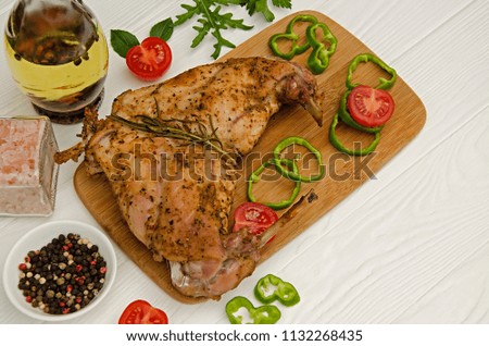 Rabbit meat baked in the oven with herbs and rosemary on a wooden board. Dietary food.