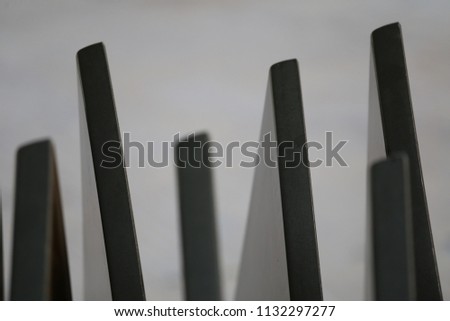 Abstract outdoor image of folded tables in a vertical orientation. Pattern of black elements composing parallel lines with a white background. Graphic picture of exterior equipment.