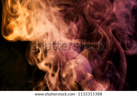 Colorful  yellow, orange and pink  smoke  on a black isolated background. Background from the smoke of vape
