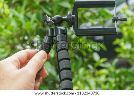 close up hold tripod for mobile phone for photographs with green nature backdrop