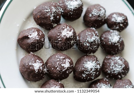 Photograph of handmade vegan truffles in the home kitchen with grated coconut on top. Completely vegetable and chocolate.