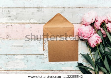 Flat lay empty card invitation with envelope. Festive background with sweet pink peonies flowers .Top view with place for text. 
