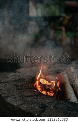 Flame and smoke of fire in the stone hearth of the country