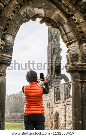 Tourist women taking pictures of the ruins of St Andrews Cathedral , Scotland.