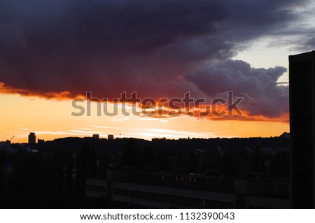 thunderclouds on the red sunset in the city