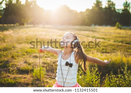 fine girl listening music with headphones and dancing, cute child enjoying music and resting Royalty-Free Stock Photo #1132415501