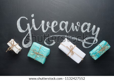Inscription Giveaway written on the board with gifts Royalty-Free Stock Photo #1132427552