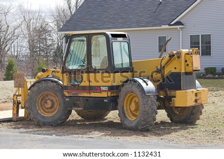 Yellow heavy construction equipment, a bulldozer, at a residential new home construction site. Horizontal orientation with copy space for text.  