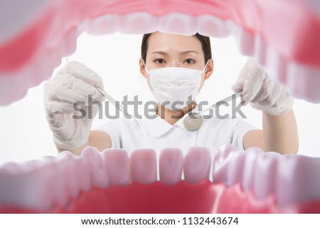 Woman wearing a white uniform looking at teeth with dental instruments