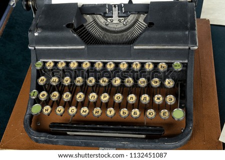 Old vintage typewriter with Russian font and a blank sheet of paper inserted.