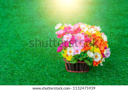 Beautiful artificial flowers blooming on green grass in the park