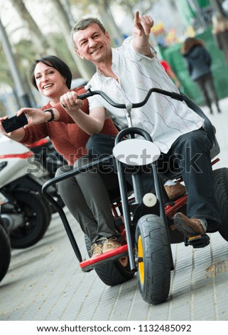 Mature couple 45s driving double bike outside and making photos