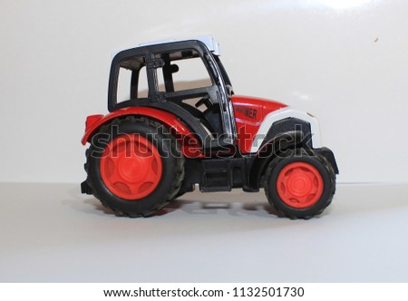 Closeup shot Of Small Red Agricultural Toy Tractor with white background, Icon Farmer Machinery, Agriculture Business Concept.