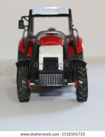 Closeup shot Of Small Red Agricultural Toy Tractor with white background, Icon Farmer Machinery, Agriculture Business Concept.