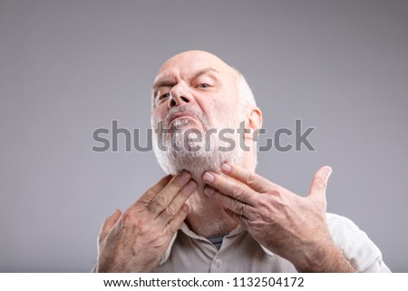 mature man checking for spots or if its beard is good enough to go out