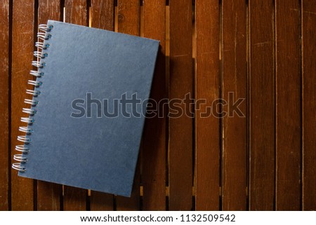 Dark blue closed hardcover book on wooden table. Top view with copy space 