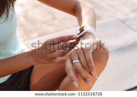 Cropped photo of young sports woman outdoors on the beach looking at watch.