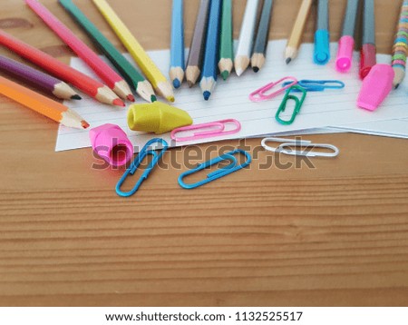 Colored pencils, paper clips, markers, note pads and erasers laying on a wooden desk, School and Office supplies, Back to school, Kindergarten