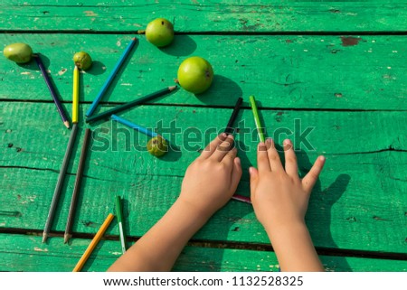 the child draw picture with colorful pens,apples and flowers on the wooden green table in the nursery or school for activity concept. creative ideas for child development.
