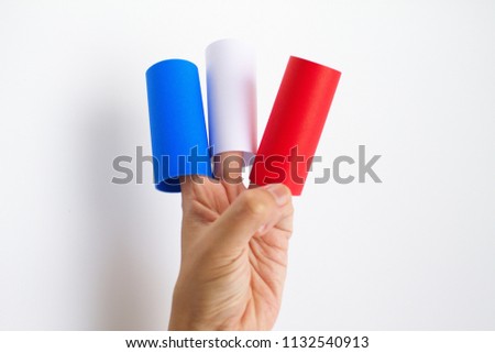 Image of rolls of papers in blue, white, and red with human fingers asserted,  composed as a background. The image giving senses of colorful visual sensation and the flag of France.