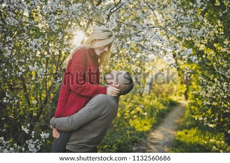 Lovers hugging on the background of flowering trees.
