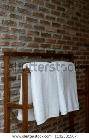 Towels in wooden rack with brick wall background in bathroom