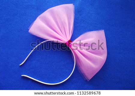 Girlish background. Pink bow with paillettes on a hair band on a blue background. It's a girl. Happy Birthday. Hen-party. Top view. Copy space. Flatlay.