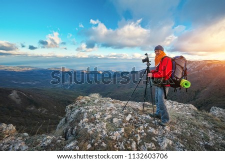 Photographer takes pictures on top of the mountain in autumn. Traveler with backpack enjoying a view from the mountain top