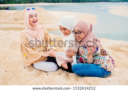 portrait of pretty asian muslim woman having fun in the beach together with friends